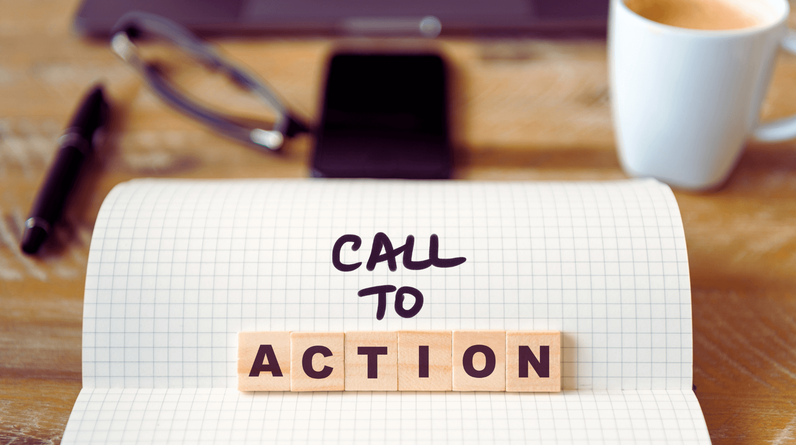 Call to Action’ spelled on a notebook over a wooden table, illustrating one of the small business website essentials